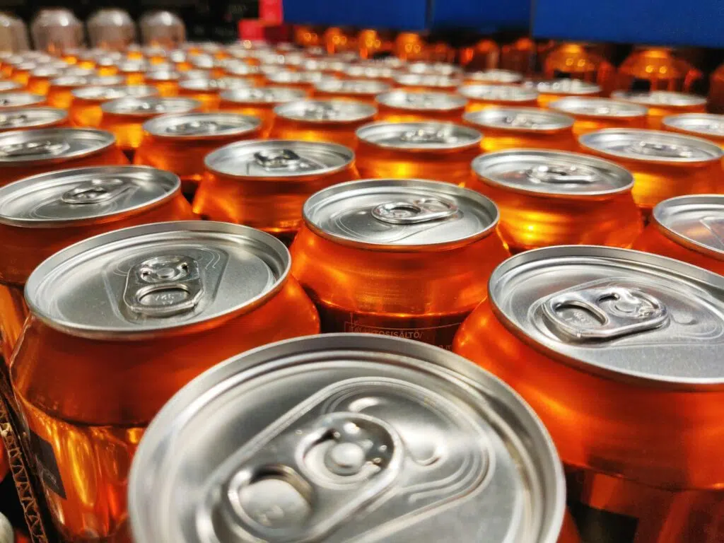 Selective focus shot of shiny orange cans production line at a factory
